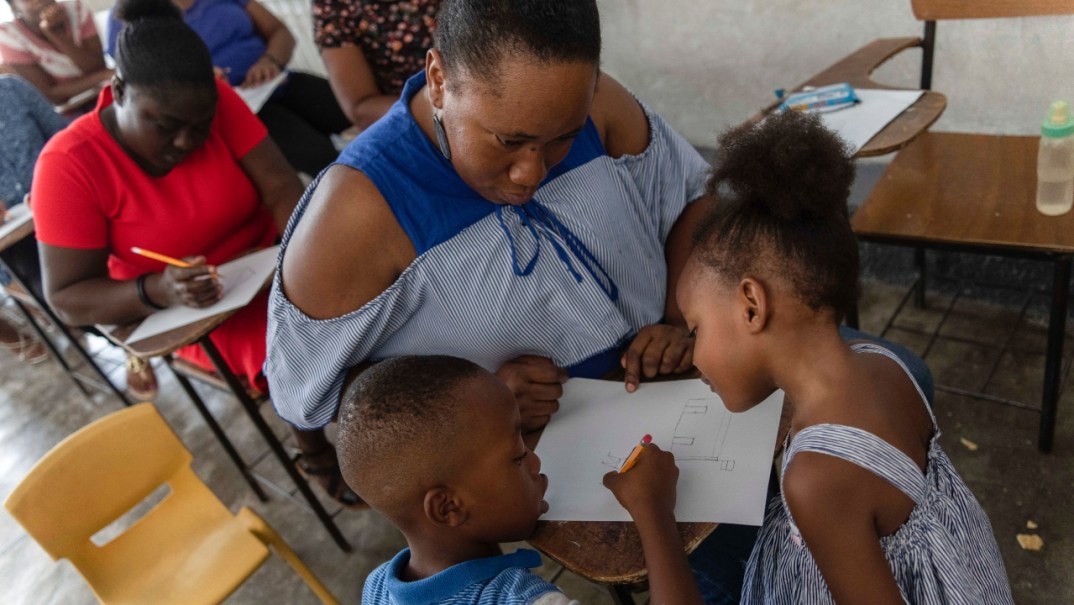 Guirlaine Reveil watches her son Jadlenzky Louis write about a drawing she made by her daughter Nhora Lynn Fedorat Louis