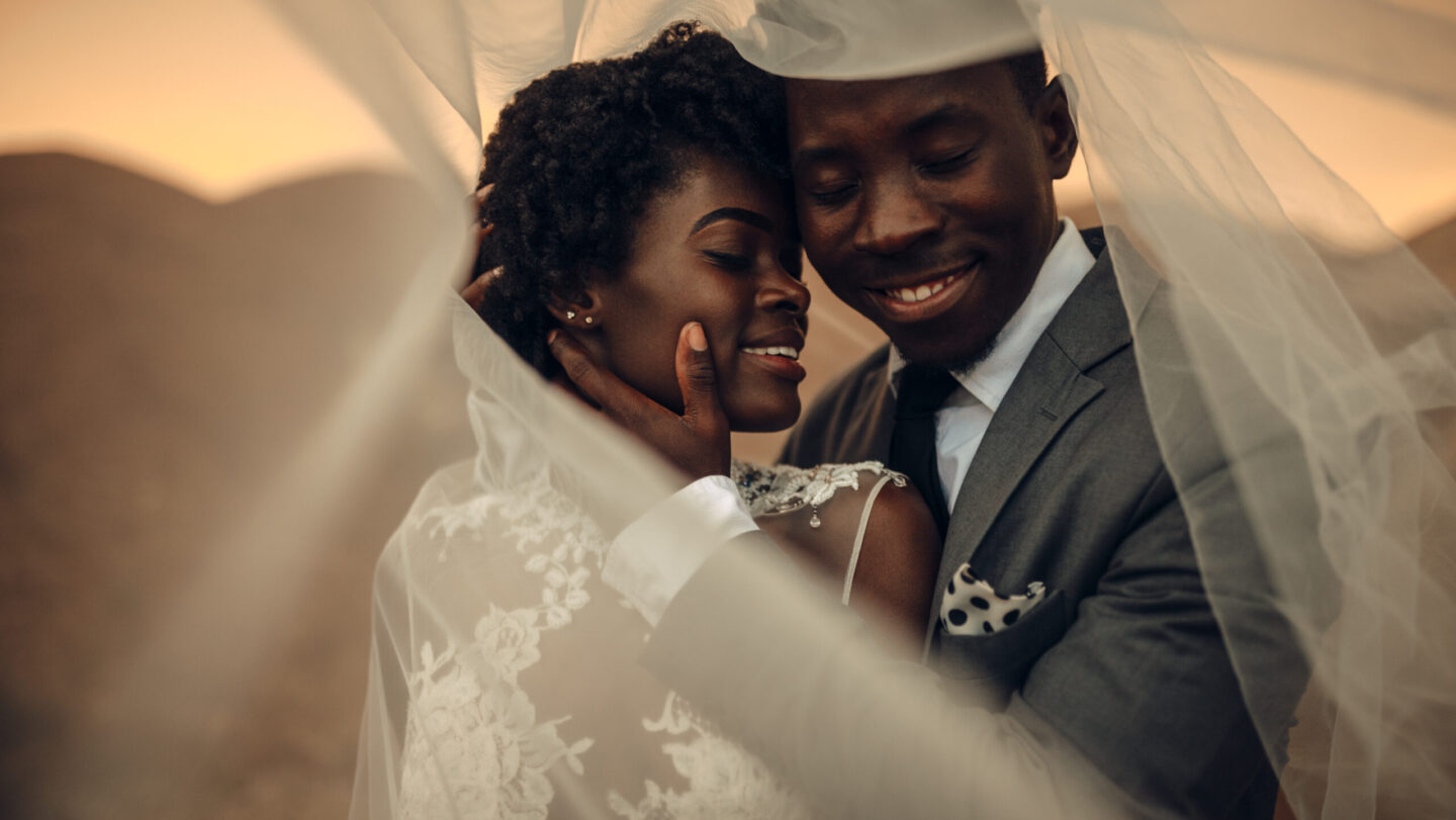 Newlyweds stand under bridal veil, embrace and smile in canyon a Black-owned brands, Black-owned wedding vendors, theGrio.com