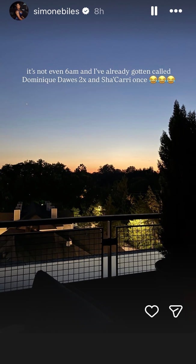 Screenshot of Simone Biles’ Instagram Story showing a sunrise view from a hotel balcony overlooking a city skyline. Over the image, Biles writes, “it’s not even 6am and i’ve already gotten called Dominique Dawes 2x and Sha’Carri once,” followed by several laughing emojis.